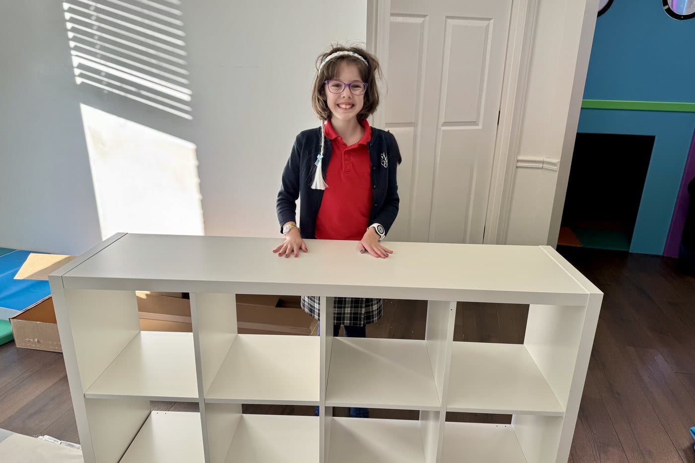 A child in the Midsouth Therapy Group occupational therapy room, standing at a shelf she has just helped put together
